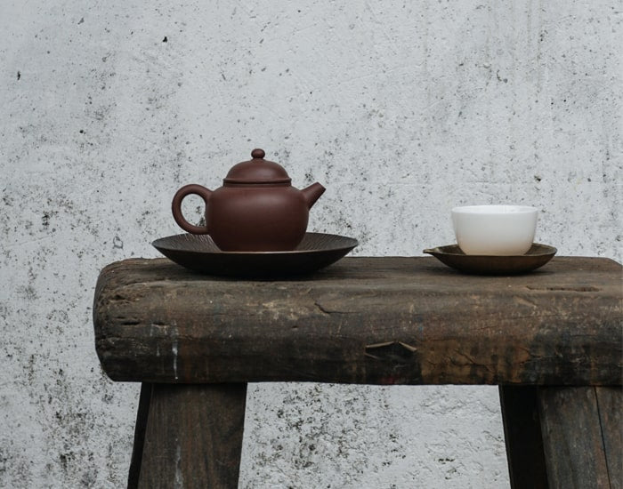 Teapot and Cup sat on a Wooden Bench.